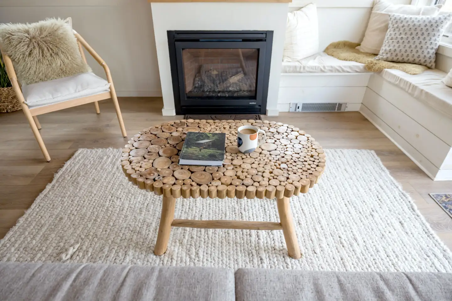 A designed living room with a fireplace, a book, and a cup of coffee.